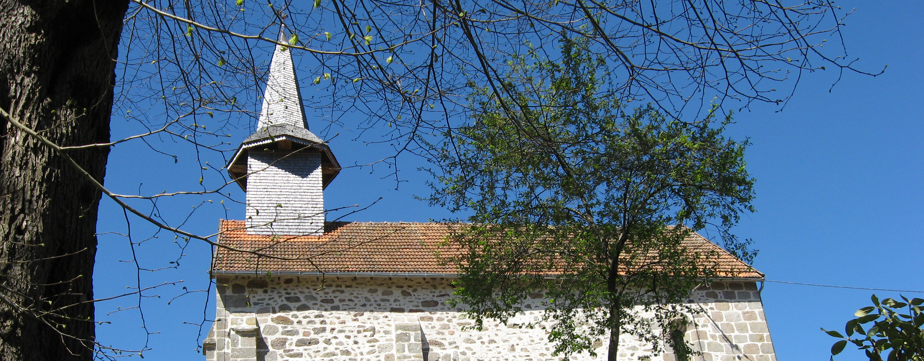 View of church at Etang de Azat-Chatenet fishing lake in France